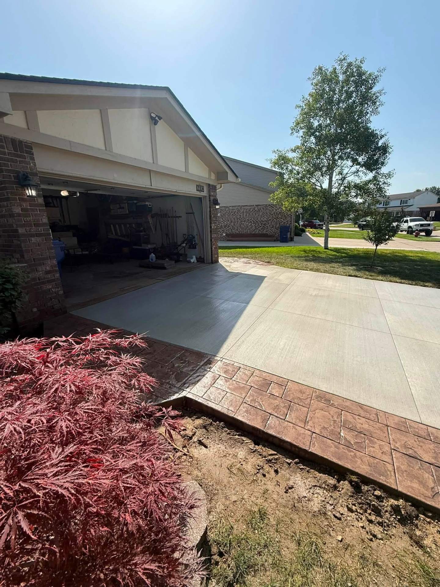 New concrete driveway with stamped brick-pattern border at garage entry