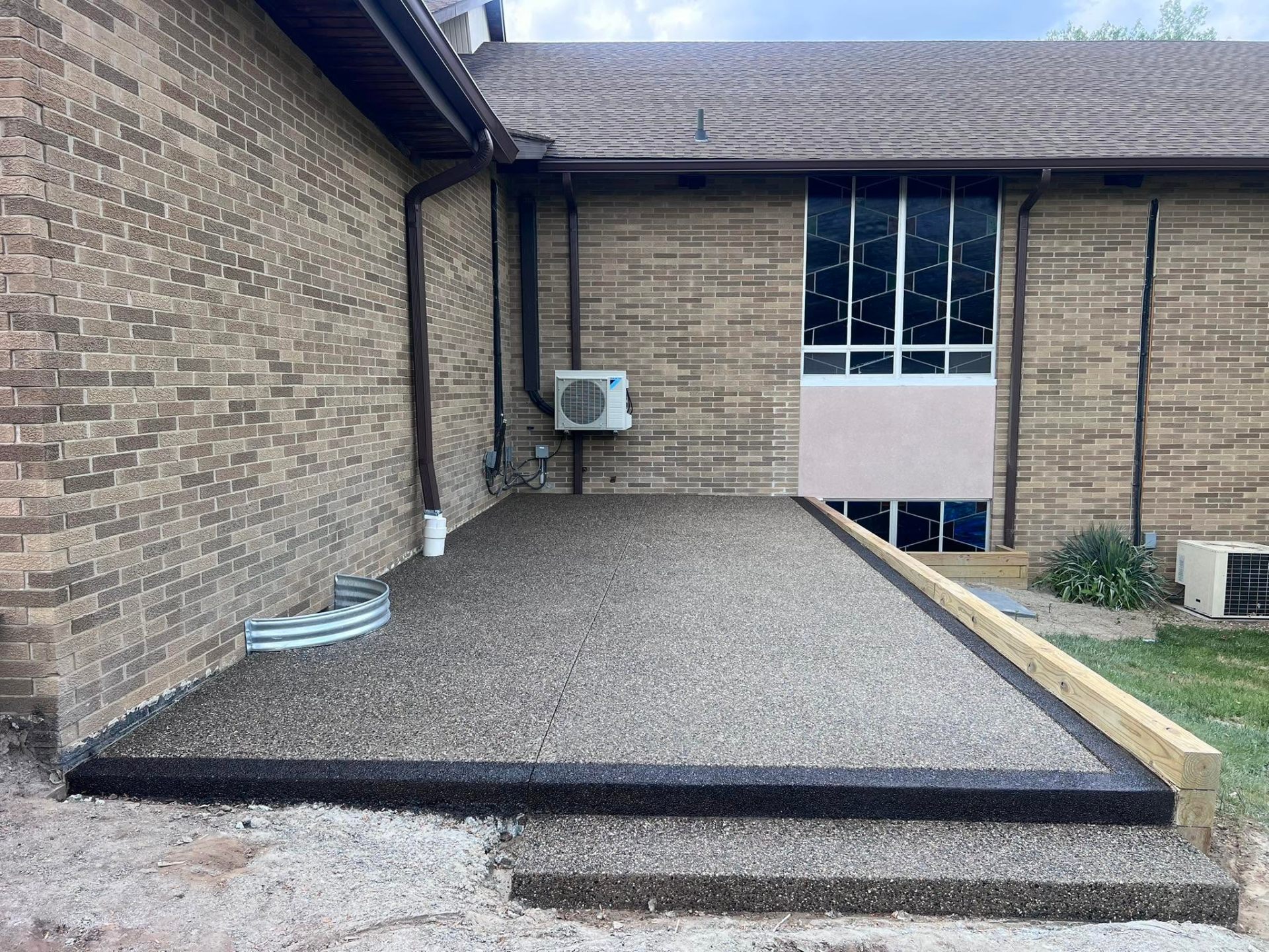 Exposed aggregate patio alongside a brick commercial building