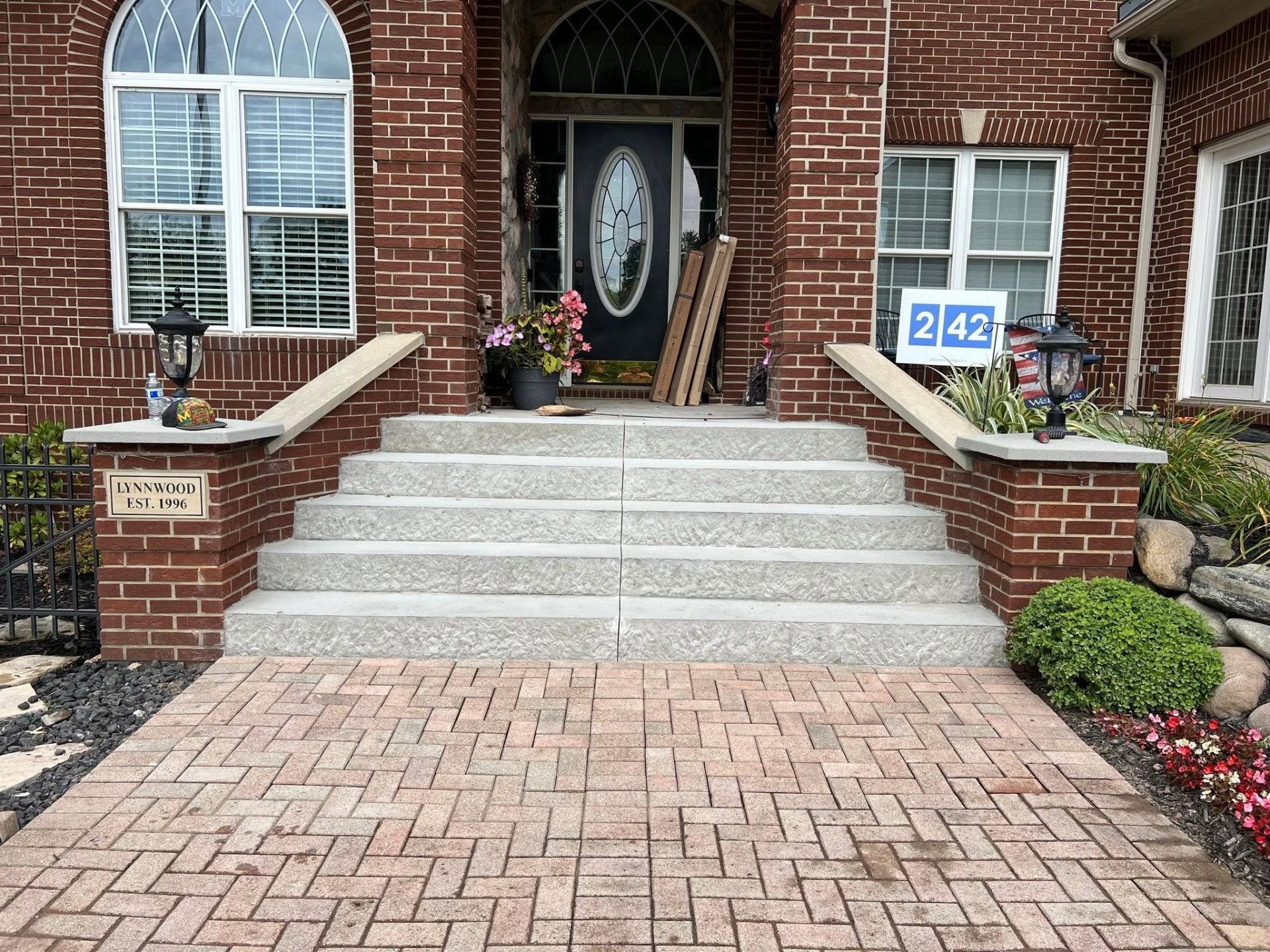 Front entry with new textured concrete steps and herringbone brick paver walkway