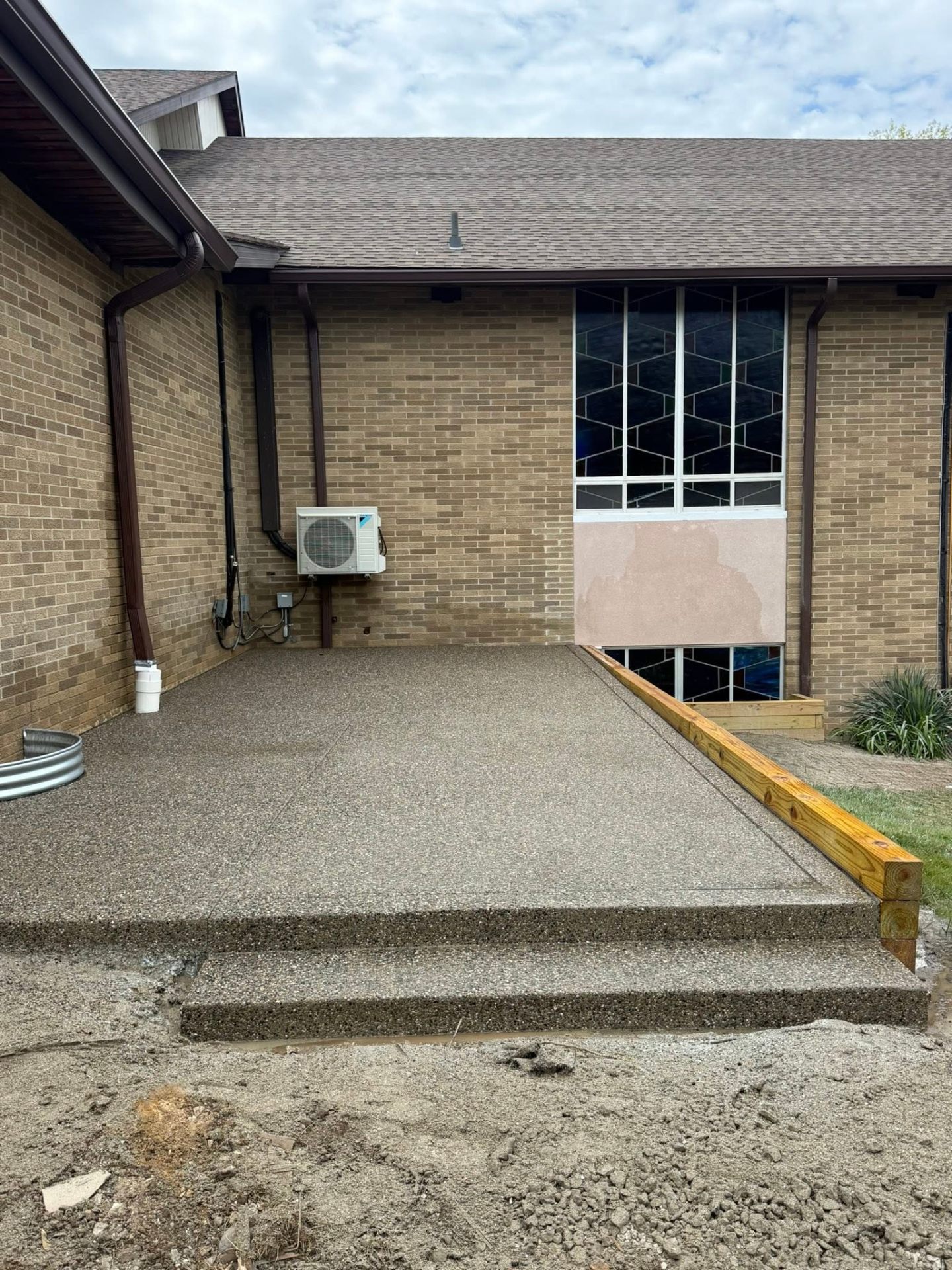 Exposed aggregate patio and steps at brick building entry