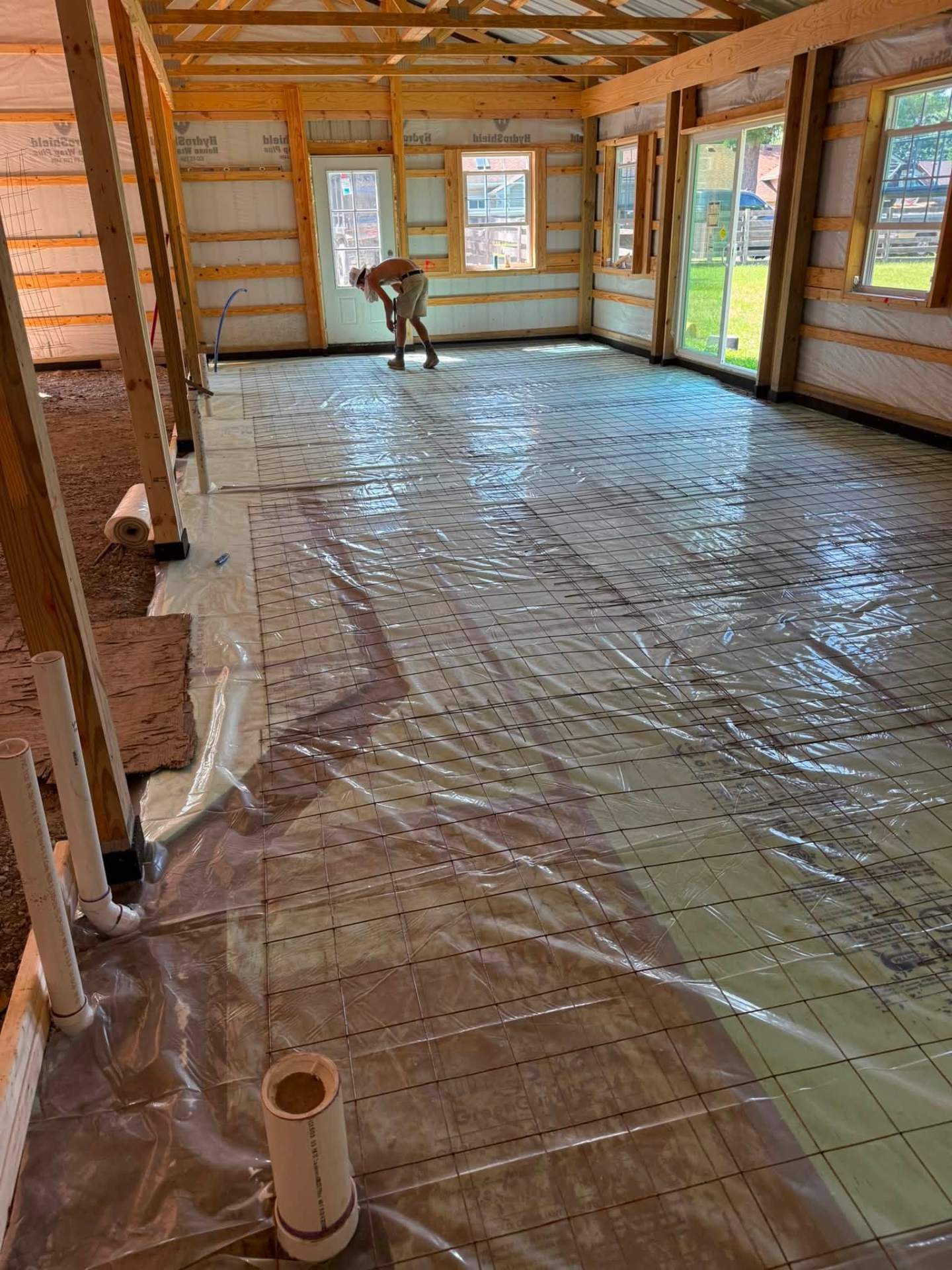 Barn floor prep — vapor barrier and tied rebar grid ready for pour
