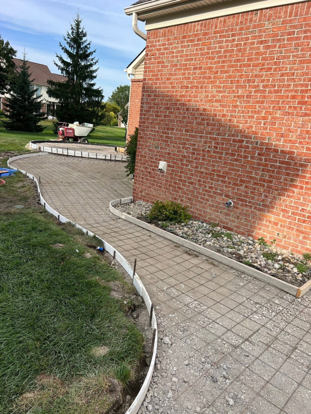 Curved walkway prep — wire mesh and forms along brick wall