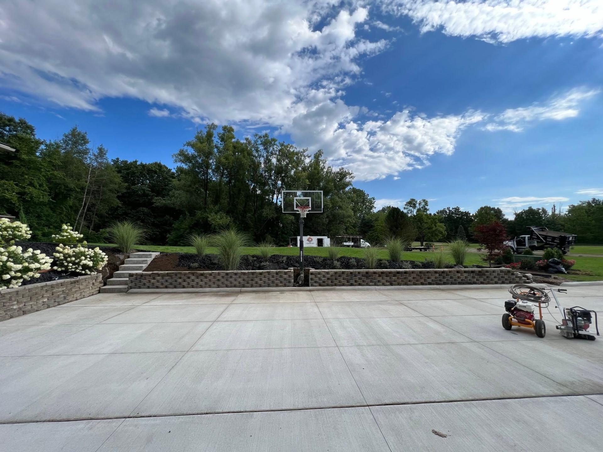 Brick and block retaining wall with steps and a basketball court in a residential backyard